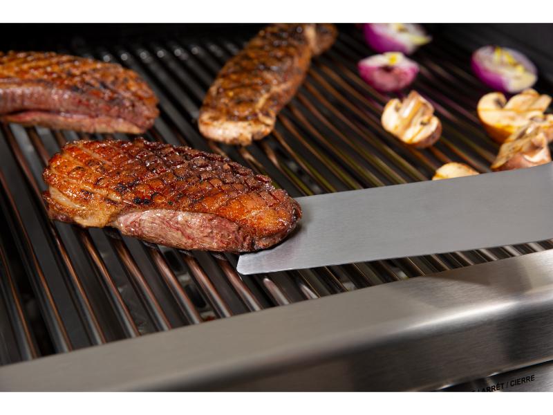 Grilled meat and vegetables on a barbecue with tongs