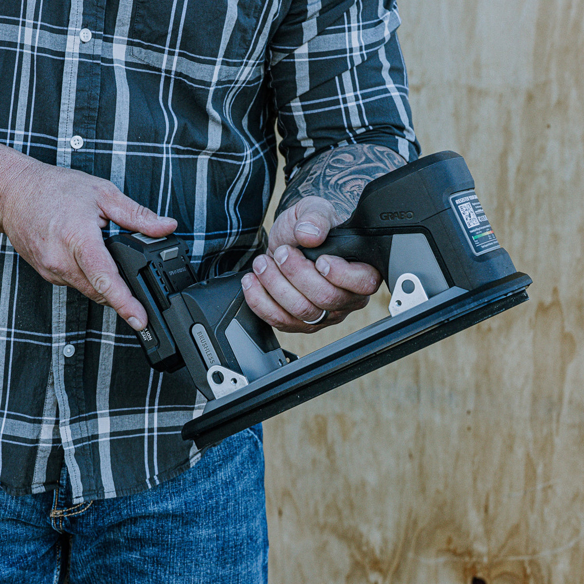Person holding a GRABO Pro Brushless 20V 2.6Ah Li-Ion Replacement Battery against a wooden background