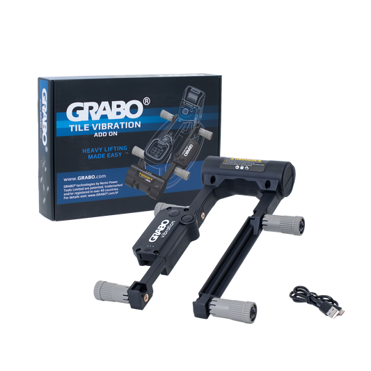 A black and gray GRABO Tile Vibration Add-On accessory with gray foot pads, shown alongside its blue and white retail box and a small USB cable on a white background.